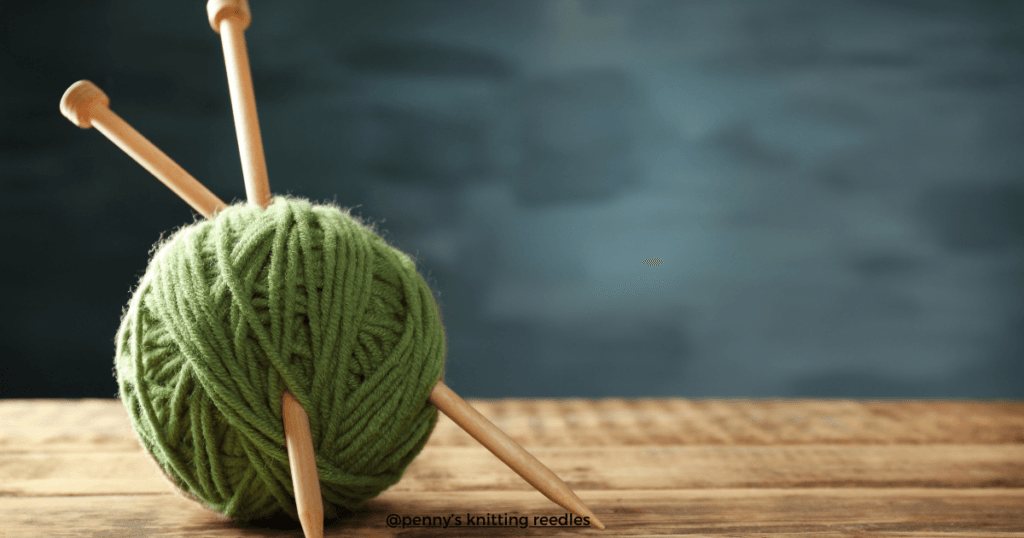 Two single-pointed knitting needles resting inside a soft bundle of yarn on a rustic wooden background, creating a cozy and inviting crafting scene.